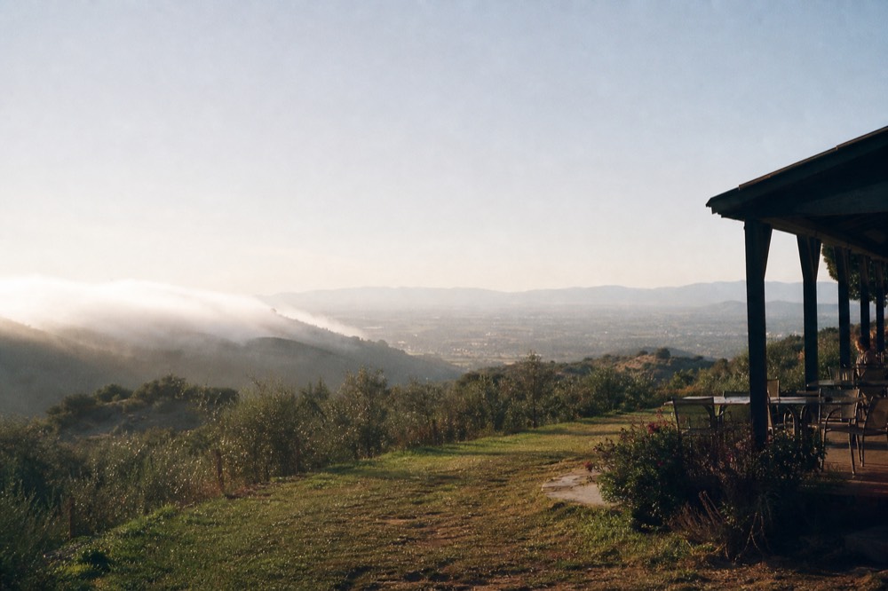 Low morning fog hanging over coastal hills with the inland valley bright and clear beyond the ridge, no text, no logos, no people
