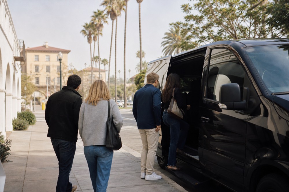A small group boarding a touring van on a downtown Santa Barbara street lined with palm trees in bright morning light, no text, no logos, no people